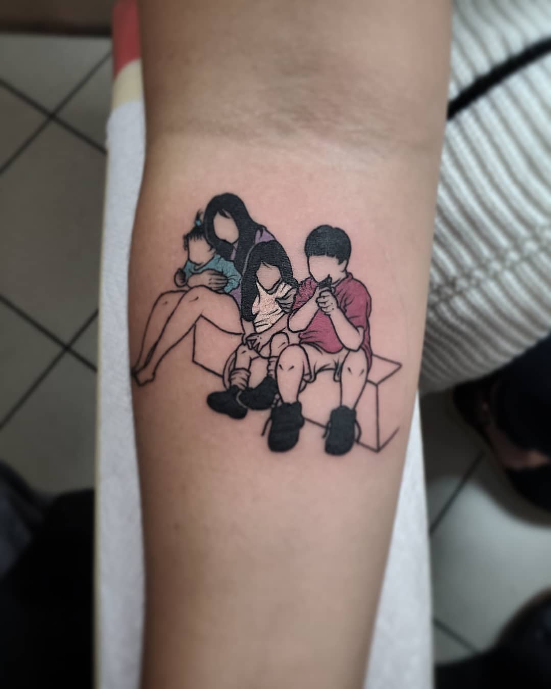 Tattoo depicting a family of four sitting and eating together on a bench